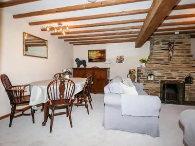 a living room with a table and a fireplace at 4 Mowhay Cottages in Saint Goran