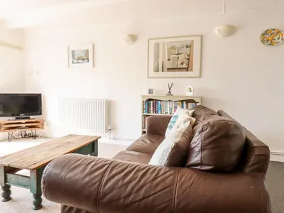 a living room with a brown leather couch and a table at Slate Cottage in Helland