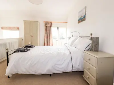 a bedroom with a large white bed and a window at Slate Cottage in Helland