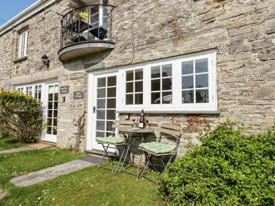 a table and chairs in front of a stone house at Slate Cottage in Helland