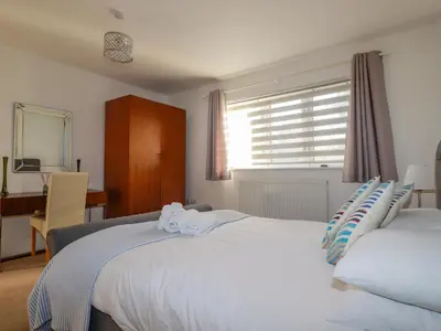 a bedroom with two beds and a desk and a window at 47 Bredon Court in Newquay