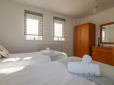 two beds in a bedroom with white sheets and towels at 47 Bredon Court in Newquay