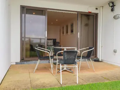 a patio with a table and chairs in front of a building at 47 Bredon Court in Newquay