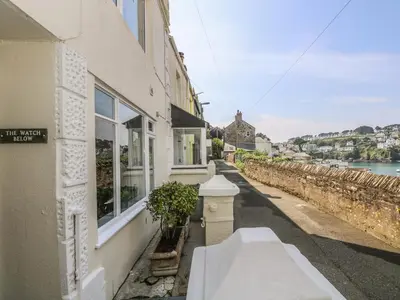 a building with a window and a plant on a street at The Watch Below in Polruan