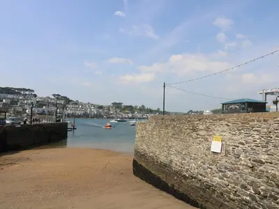 a stone wall next to a body of water with boats at The Watch Below in Polruan