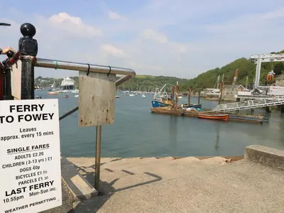 a sign next to a marina with boats in the water at The Watch Below in Polruan