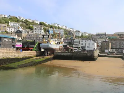 a boat is docked in a harbor with houses at The Watch Below in Polruan