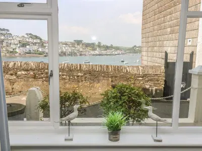 two birds sitting on a window sill looking out at the water at The Watch Below in Polruan