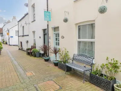 a bench sitting outside of a building with plants at Curlews Cottage in Looe