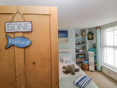 a bedroom with a bed and a sign that says gone fishing at Curlews Cottage in Looe