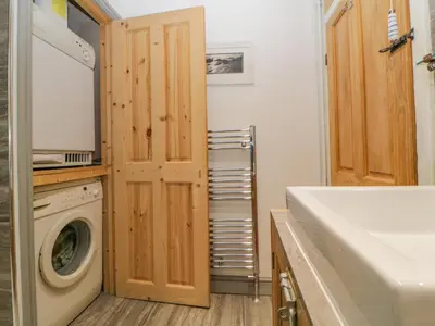 a laundry room with a washing machine and a washer at Curlews Cottage in Looe