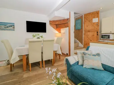a living room with a couch and a table at Curlews Cottage in Looe