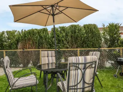 a patio table and chairs with an umbrella at 11 Pendarves in St Merryn