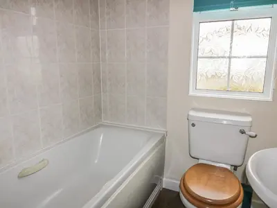 a bathroom with a tub and a toilet and a window at 11 Pendarves in St Merryn