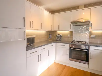 a kitchen with white cabinets and stainless steel appliances at 11 Pendarves in St Merryn