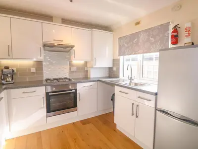 a kitchen with white cabinets and stainless steel appliances at 11 Pendarves in St Merryn