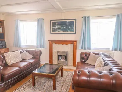 a living room with two leather couches and a fireplace at 11 Pendarves in St Merryn
