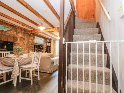 a staircase in a room with a table and a dining room at Tinners Cottage in Saint Cleer