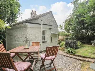 a wooden table and chairs in front of a cottage at Tinners Cottage in Saint Cleer
