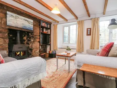 a living room with a fireplace and a stone wall at Tinners Cottage in Saint Cleer