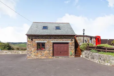 a small brick building with a red garage at The Litte Hideaway in Saint Columb Minor