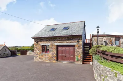 a brick house with a garage and a fence at The Litte Hideaway in Saint Columb Minor