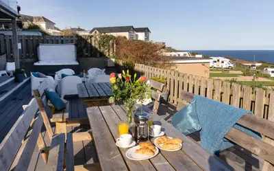 a wooden table with food and flowers on a balcony at Boscarne in St Ives