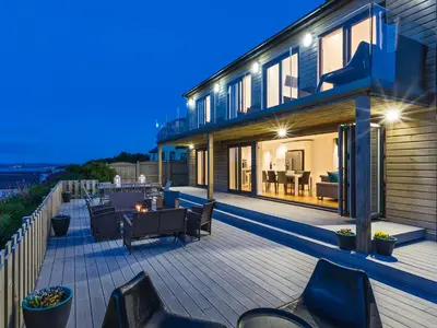 a house with a deck with chairs and a table at Boscarne in St Ives