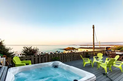 a hot tub on a deck with chairs and a table at Boscarne in St Ives