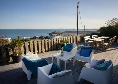 a patio with chairs and a table with a view of the ocean at Boscarne in St Ives