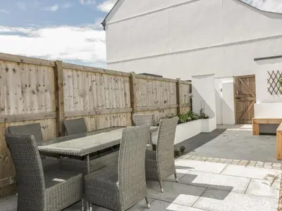 a patio with a table and chairs and a fence at 5 Ocean Heights in Newquay