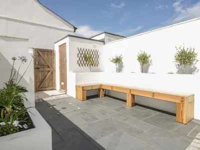 a patio with a wooden bench in front of a building at 5 Ocean Heights in Newquay