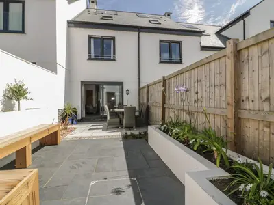 a garden with a wooden fence and a patio at 5 Ocean Heights in Newquay