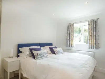 a bedroom with a white bed with pillows and a window at 7 Harlyn Cottages in St Merryn