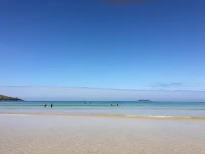 a group of people swimming in the water on a beach at 7 Harlyn Cottages in St Merryn
