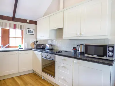 a kitchen with white cabinets and a microwave at The Bullshed in Saint Erth