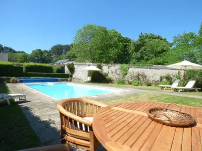 a wooden table and chairs next to a swimming pool at Flower House in Saint Erth