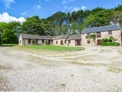 an old stone house with a gravel driveway at Flower House in Saint Erth