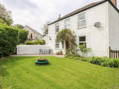 a yard with a white house with a green lawn at Angarrack Farmhouse in Hayle