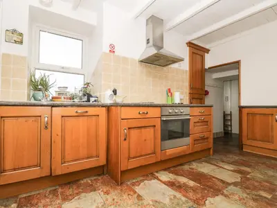 a kitchen with wooden cabinets and a stove at Angarrack Farmhouse in Hayle