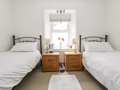 a bedroom with two beds and a window and a table at Angarrack Farmhouse in Hayle