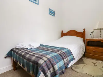 a bedroom with a bed with a plaid blanket at Angarrack Farmhouse in Hayle