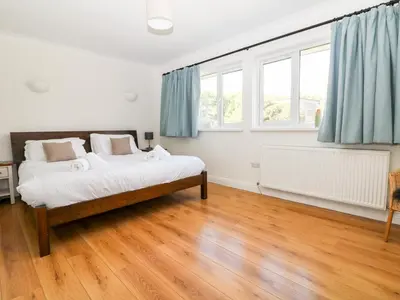 a bedroom with a bed and two windows at Seaport Lodge in Mawgan Porth