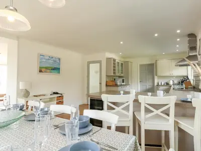 a kitchen and living room with white chairs and a table at Seaport Lodge in Mawgan Porth