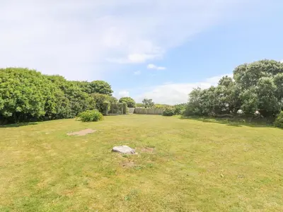 a large grassy field with a fence and trees at Seaport Lodge in Mawgan Porth
