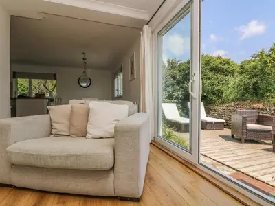 a living room with a couch and a sliding glass door at Seaport Lodge in Mawgan Porth