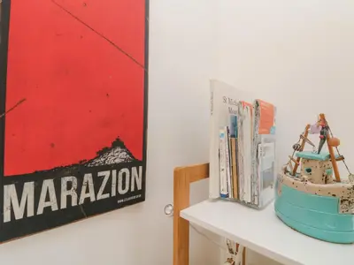 a shelf with books and a poster on a wall at Mackerel Sky in Marazion