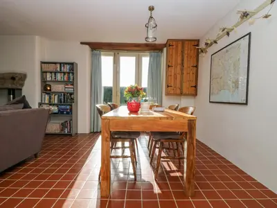 a living room with a wooden table and chairs at Woodfield Coach House in Merrymeet