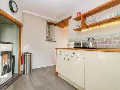 a kitchen with white cabinets and a clock on the wall at Woodfield Coach House in Merrymeet