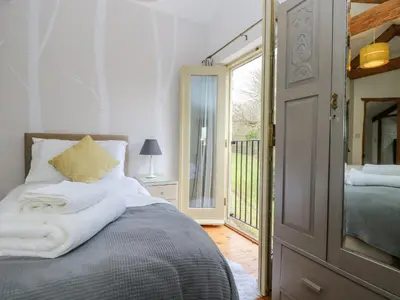 a bedroom with a bed and a door to a balcony at Woodfield Coach House in Merrymeet